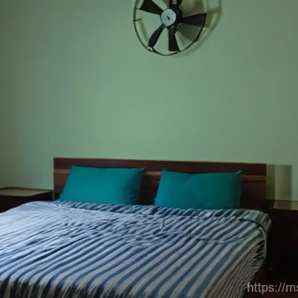 체온 조절로 수면 질 개선하기 - A young adult, looking slightly uncomfortable and restless, is in a modest bedroom at night, attempt...